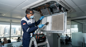 فني صيانة يقوم بتنظيف فلتر تكييف سقفي داخل مكتب